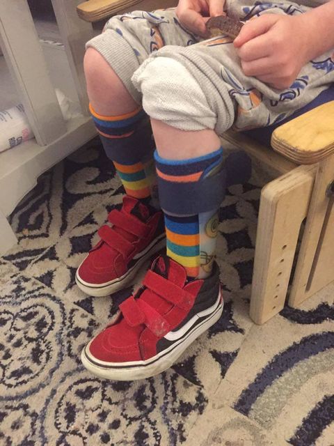 Child sitting on a wooden chair wearing rainbow striped bamboo socks with red sneakers, casual outfit, indoors setting